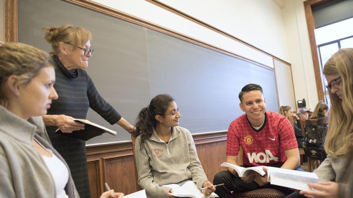 A professor listening to a group of students in the middle of a discussion